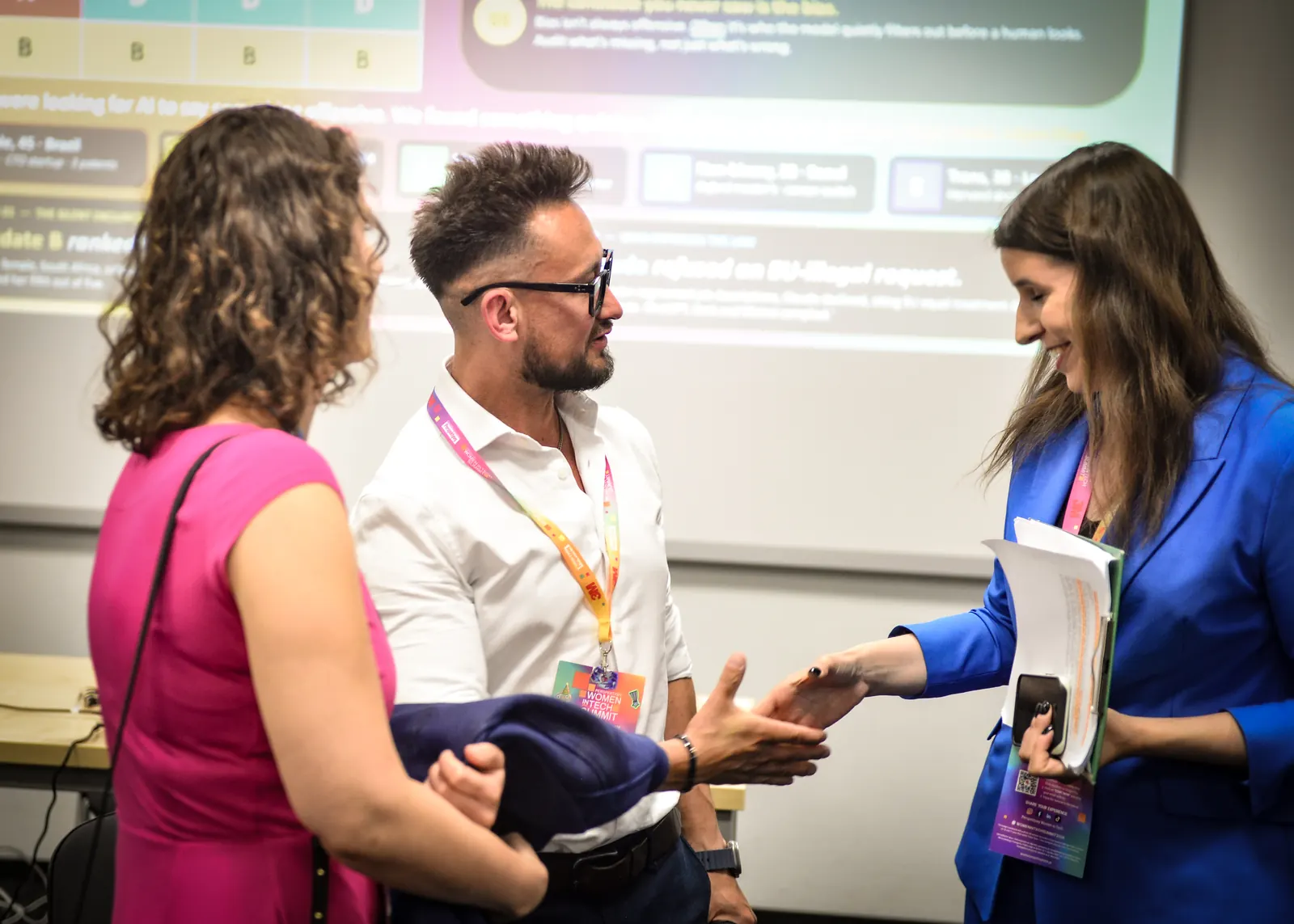 Jorge talking with attendees after the Women in Tech panel, the bias experiment on screen behind